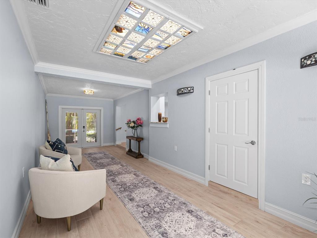 A bright entryway features light wood flooring, a stained-glass ceiling panel, and two armchairs — 502 FLORIDA BOULEVARD, CRYSTAL BEACH, FL