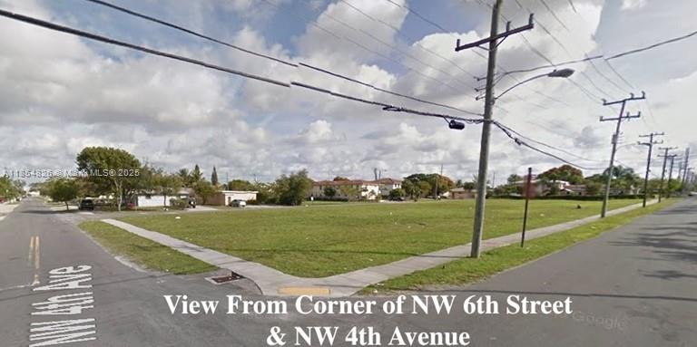 This is a street-level view of a vacant, grassy corner lot at an intersection — 6 Nw Ct, Pompano Beach FL 33060, POMPANO BEACH, FL