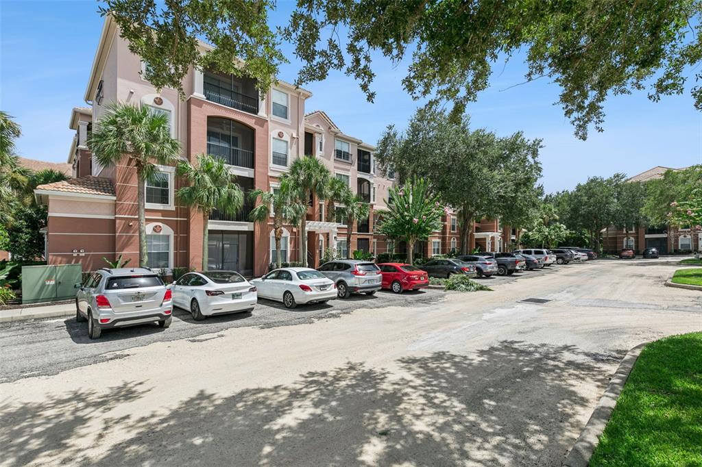 A multi-story apartment building with a parking lot in front under a blue sky — 1351 VENEZIA COURT UNIT 305, DAVENPORT, FL