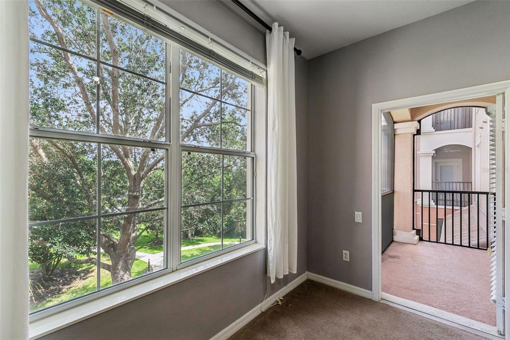 An empty room with gray walls, carpeted flooring, a large window, and a balcony door — 1351 VENEZIA COURT UNIT 305, DAVENPORT, FL