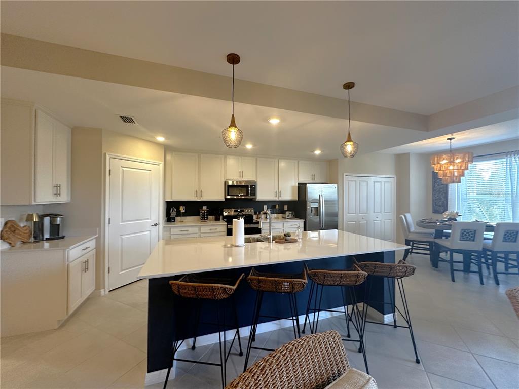 A kitchen features a large white island with dark blue cabinetry and four woven stools — 14221 HERITAGE LANDING BOULEVARD UNIT 2014, PUNTA GORDA, FL