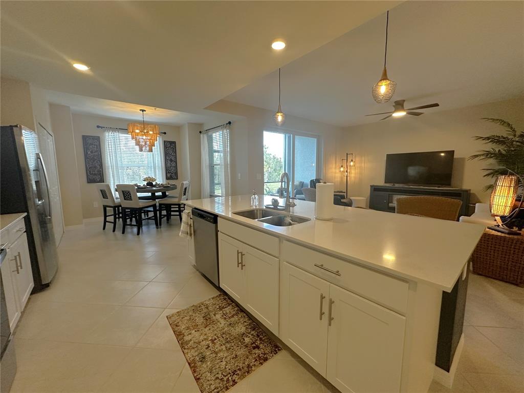 A kitchen with white cabinets and a large island overlooks an open-concept dining and living area — 14221 HERITAGE LANDING BOULEVARD UNIT 2014, PUNTA GORDA, FL