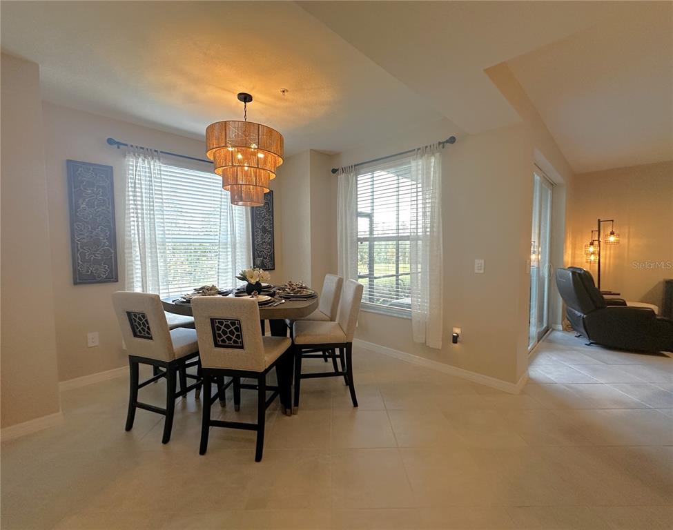 A dining area features a round table, upholstered chairs, and a tiered drum pendant light — 14221 HERITAGE LANDING BOULEVARD UNIT 2014, PUNTA GORDA, FL