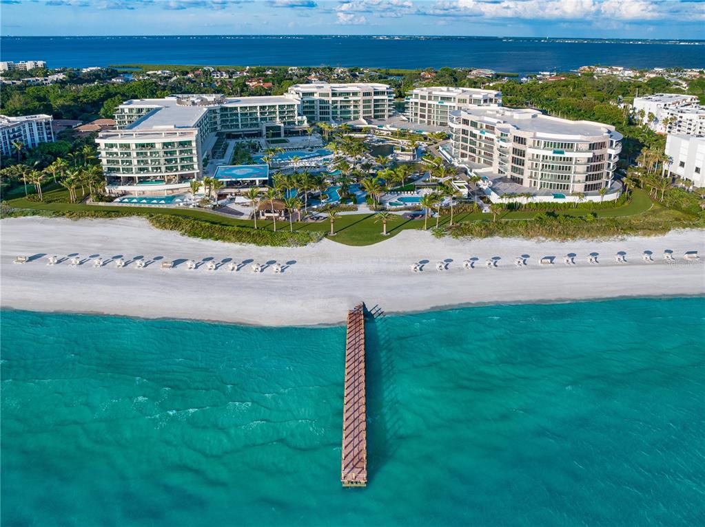 An aerial view shows a large beachfront resort complex with a pier extending into the ocean — 1591 GULF OF MEXICO DRIVE UNIT 413, LONGBOAT KEY, FL