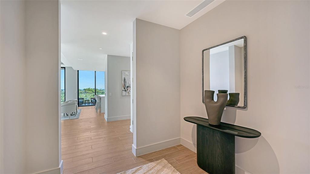 A modern entryway features a dark console table, a mirror, and light wood-look tile flooring — 1591 GULF OF MEXICO DRIVE UNIT 413, LONGBOAT KEY, FL