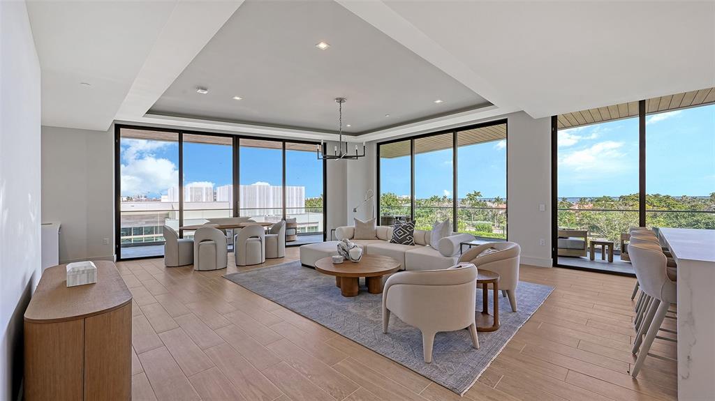 A modern living room features light wood floors, a large area rug, and floor-to-ceiling windows — 1591 GULF OF MEXICO DRIVE UNIT 413, LONGBOAT KEY, FL