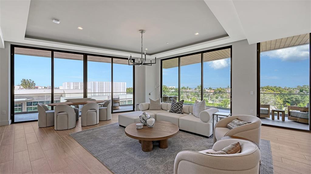 A modern living and dining area features floor-to-ceiling windows, neutral furniture, and wood flooring — 1591 GULF OF MEXICO DRIVE UNIT 413, LONGBOAT KEY, FL