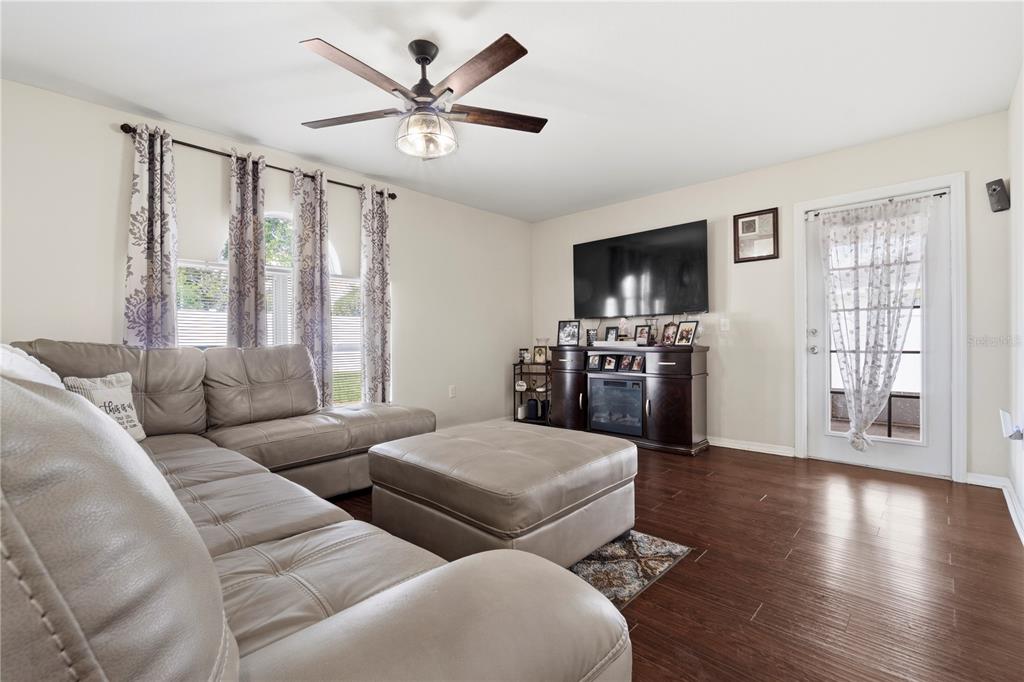 A living room features a grey sectional sofa, a television, and dark wood flooring — 2881 SW 142ND LANE, OCALA, FL