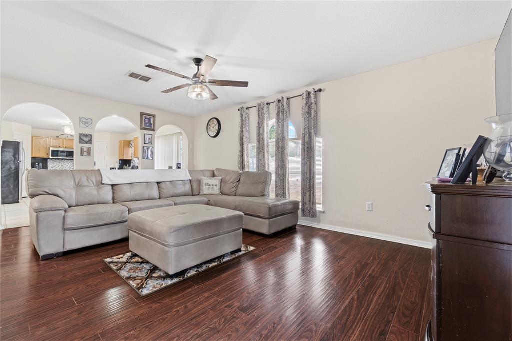 A living room features a large gray sectional sofa, an ottoman, and dark wood flooring — 2881 SW 142ND LANE, OCALA, FL