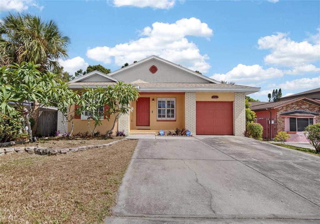 A single-story house with a yellow stucco exterior, red door, and an attached garage — 1101 27TH AVENUE S, ST PETERSBURG, FL