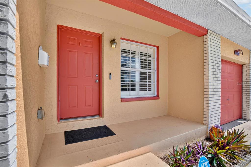 The exterior of a home features a red front door, a window with security bars, and a small porch — 1101 27TH AVENUE S, ST PETERSBURG, FL