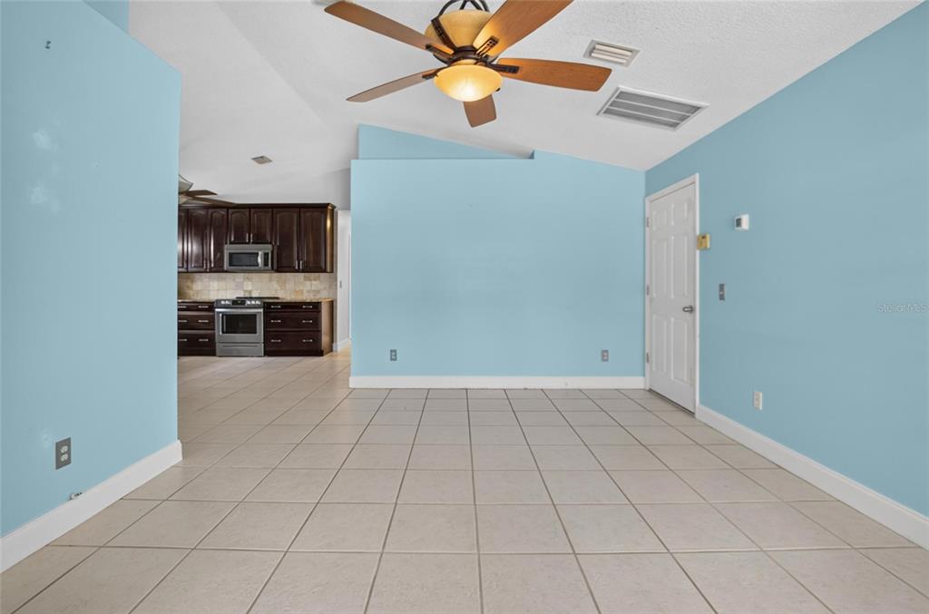 A light blue room with tile flooring, a ceiling fan, and an adjacent kitchen — 1101 27TH AVENUE S, ST PETERSBURG, FL