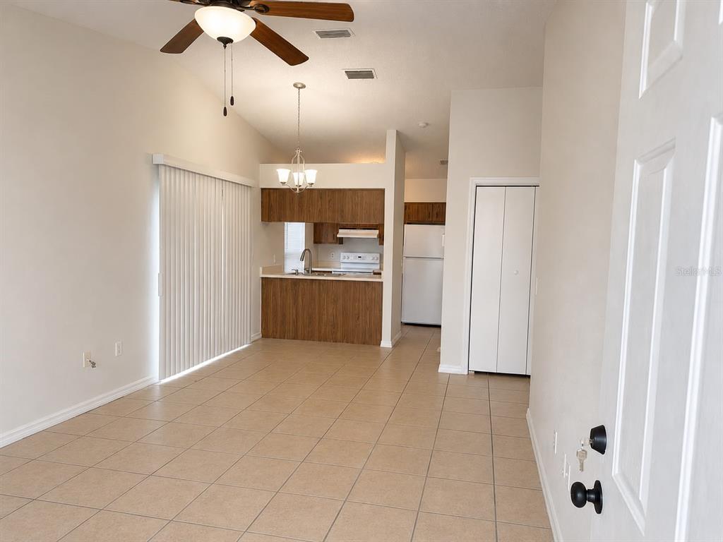 An open-concept room features tile flooring, a ceiling fan, and a kitchen with wood cabinets — 3558 SW 157TH LOOP, OCALA, FL