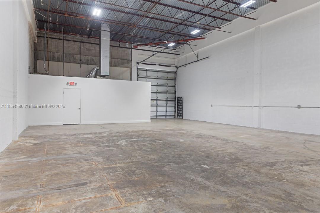 This industrial warehouse space features a concrete floor, high ceilings, and a roll-up garage door — 1501 NW 82nd Ave, Doral FL 33126, DORAL, FL