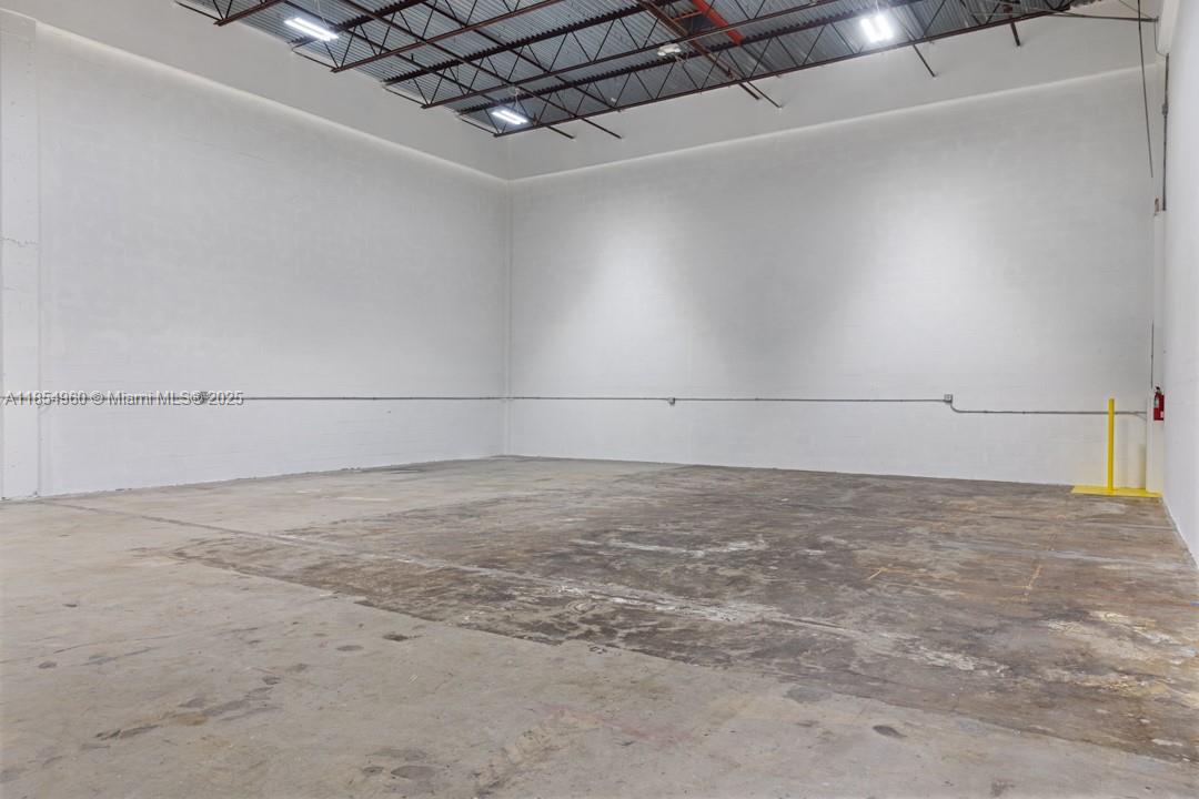 An empty industrial warehouse space features white walls, a concrete floor, and exposed ceiling lights — 1501 NW 82nd Ave, Doral FL 33126, DORAL, FL