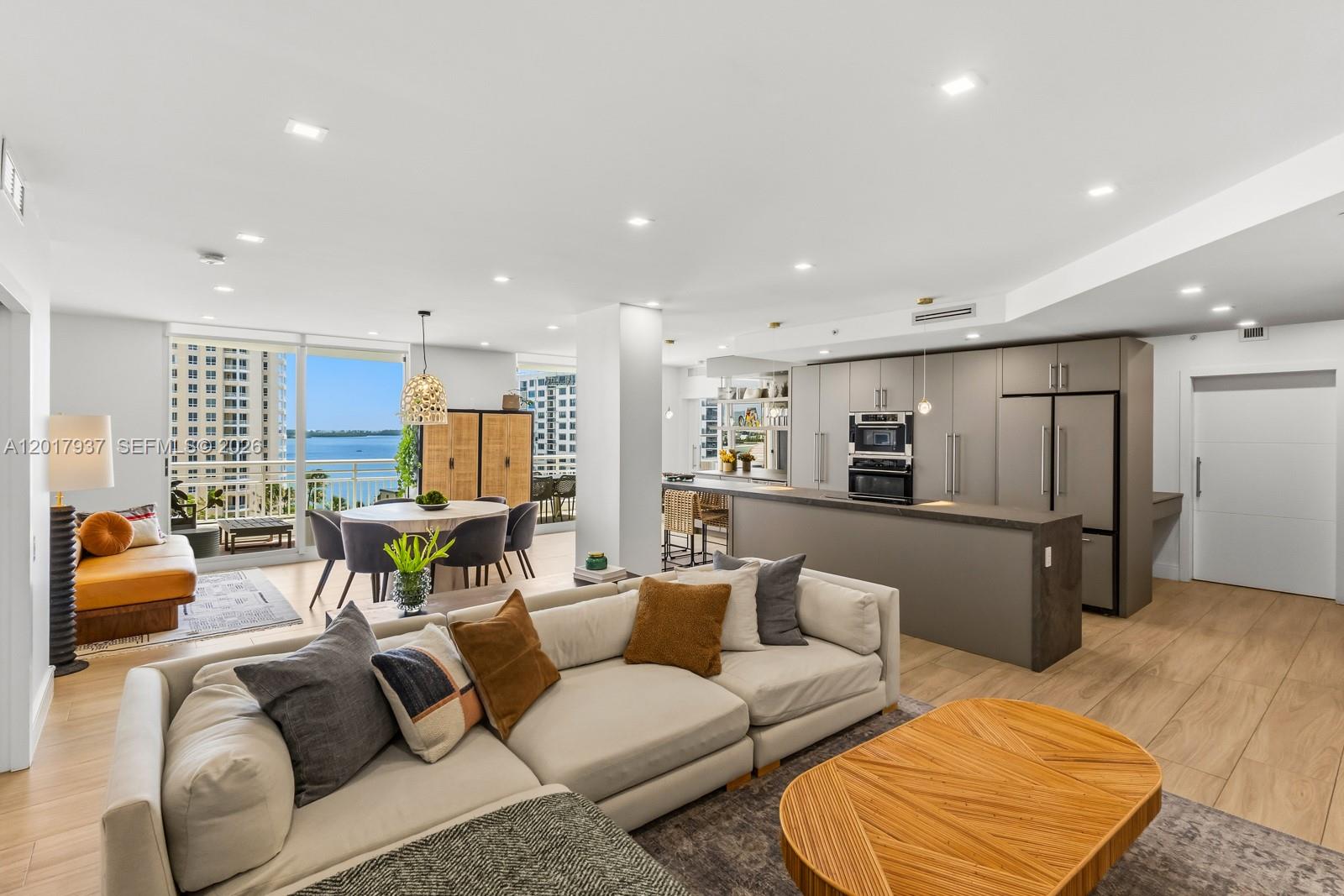 An open-concept living area features a modern kitchen, dining space, and balcony with water views — 888 Brickell Key Dr # 1207, Miami FL 33131, MIAMI, FL