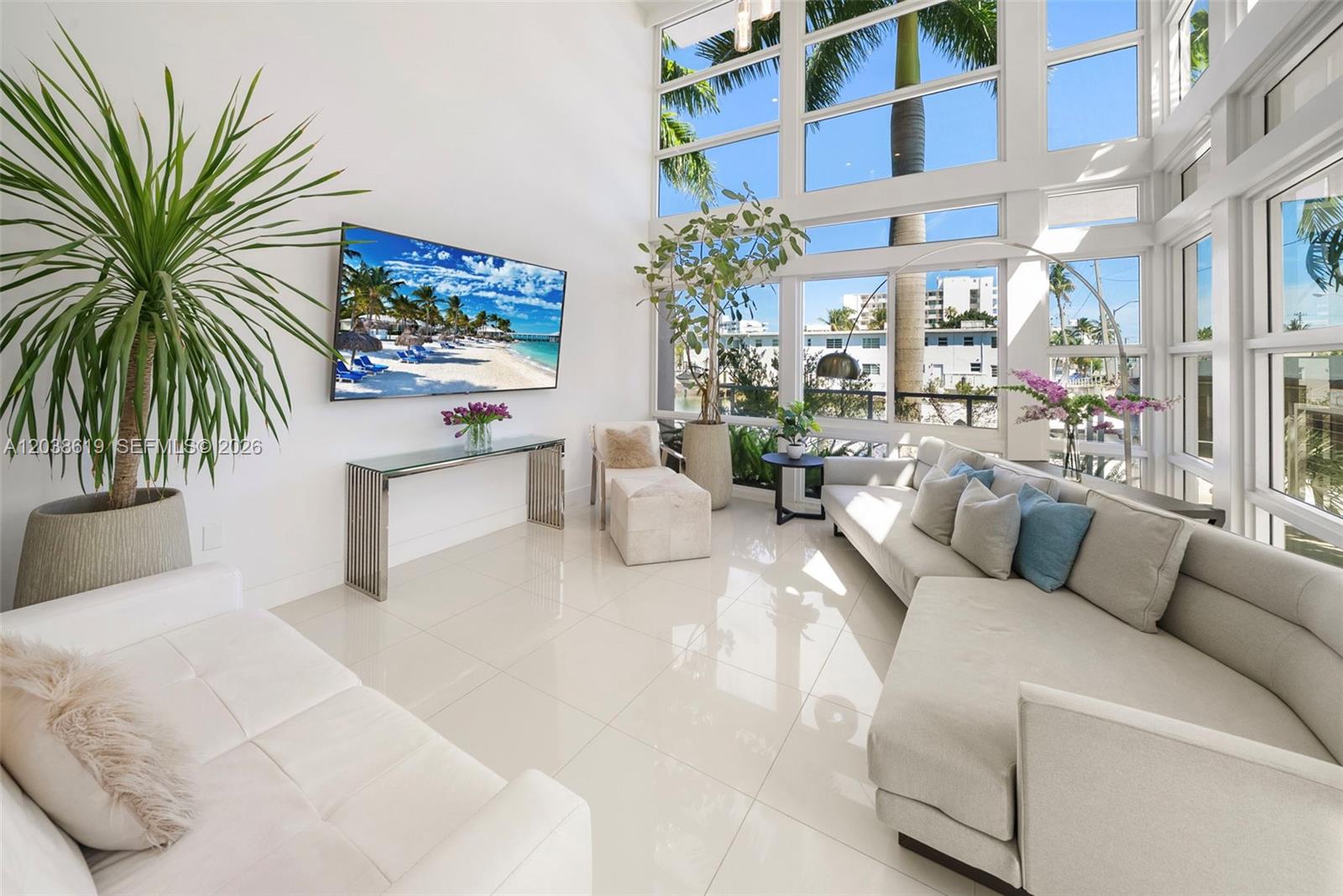 A bright living room features high ceilings, floor-to-ceiling windows, white tile floors, and modern furniture — 39 N Shore Dr, Miami Beach FL 33141, MIAMI BEACH, FL
