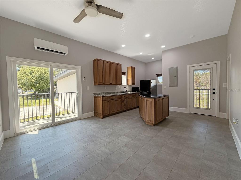 A kitchen with wood cabinets, a center island, and tile flooring opens to a patio — 706 NEW YORK AVENUE, ST CLOUD, FL