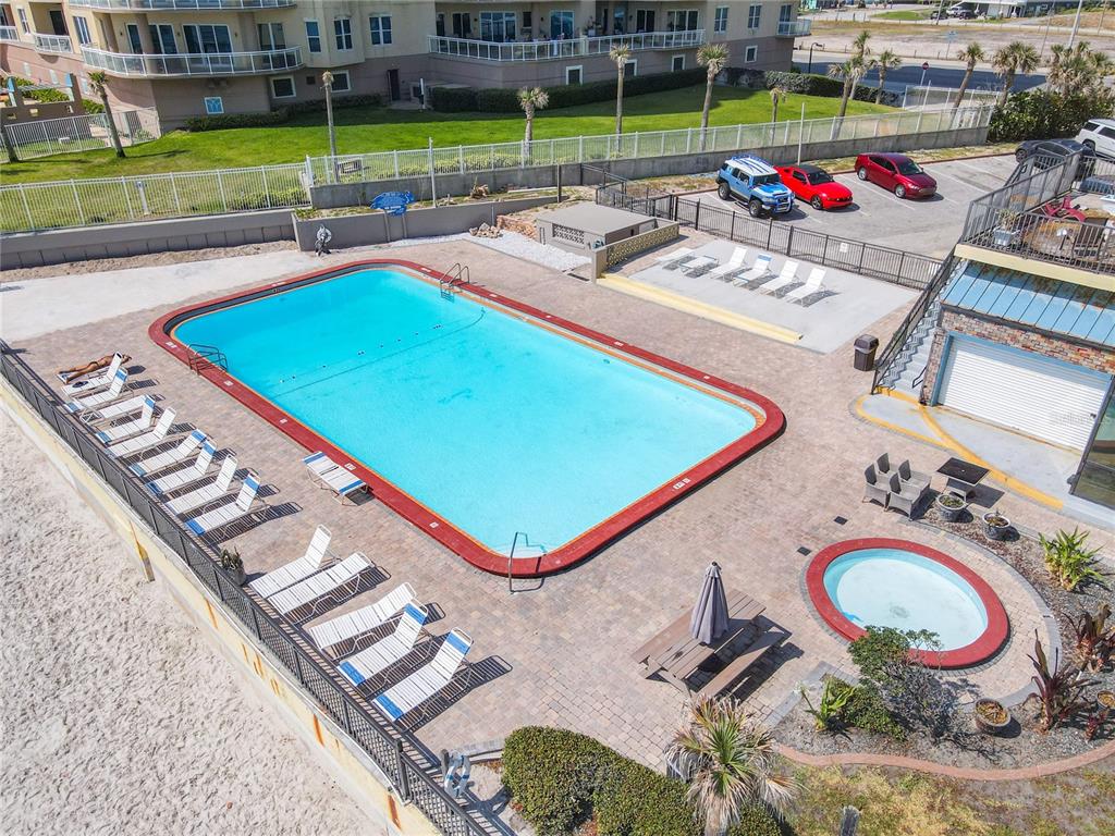 An aerial view shows a rectangular swimming pool, a small circular hot tub, and lounge chairs — 1909 S ATLANTIC AVENUE UNIT 402, DAYTONA BEACH, FL