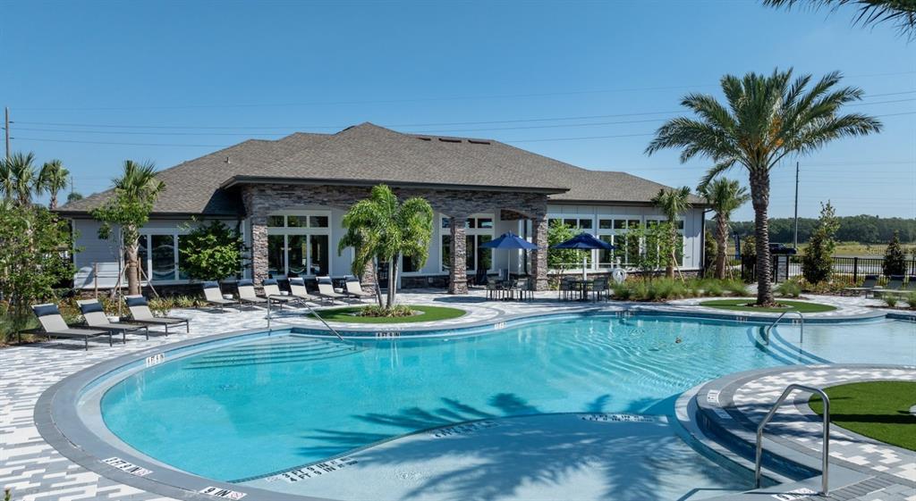 A swimming pool with lounge chairs and a clubhouse exterior under a clear blue sky — 3110 GOWAN DRIVE UNIT B1, WINTER HAVEN, FL