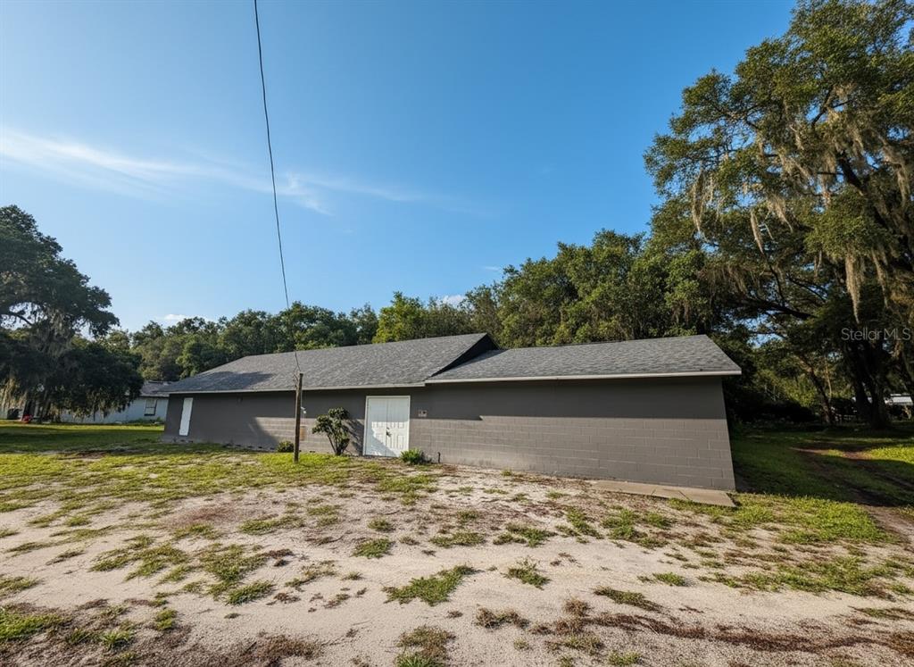 A single-story gray concrete block building with a shingled roof sits on a sandy lot — 601 KILGORE STREET, WILDWOOD, FL