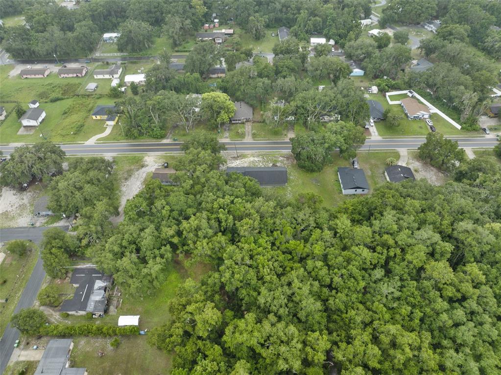 An aerial view shows a residential neighborhood with houses surrounded by dense trees and roads — 601 KILGORE STREET, WILDWOOD, FL