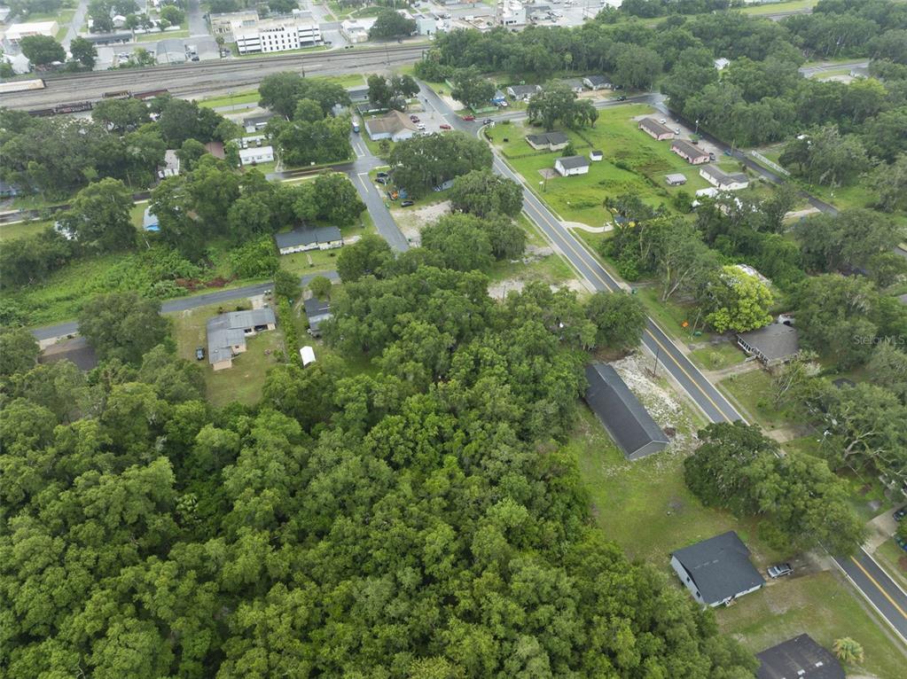 An aerial view shows a wooded lot surrounded by residential houses and nearby railroad tracks — 601 KILGORE STREET, WILDWOOD, FL