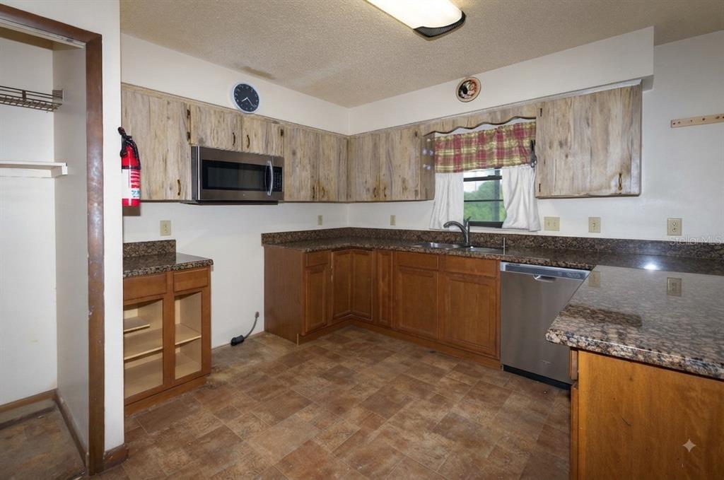 A kitchen features two-toned cabinets, granite countertops, a stainless steel dishwasher, and a microwave — 1723 BRANGUS DRIVE, LAKELAND, FL