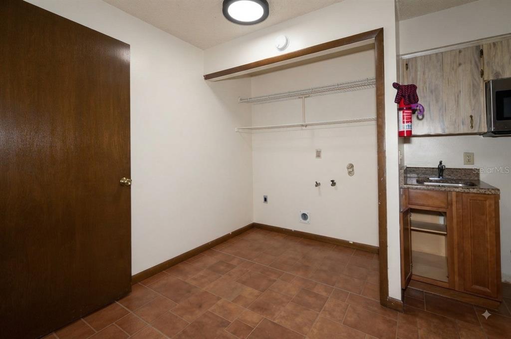 A laundry room features tile flooring, a utility sink, and open wire shelving — 1723 BRANGUS DRIVE, LAKELAND, FL