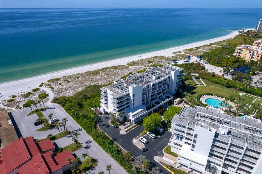 An aerial view shows a multi-story beachfront condominium complex with a pool and parking lot — 2105 GULF OF MEXICO DRIVE UNIT 3404, LONGBOAT KEY, FL