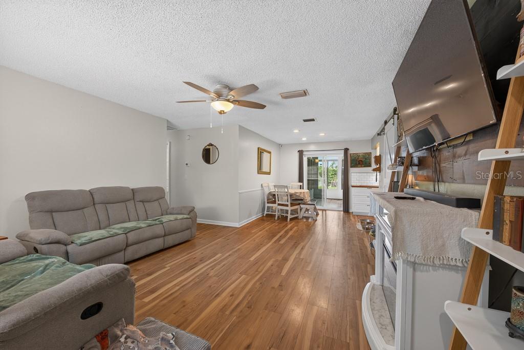 A living room features wood-look flooring, a gray sofa, a fireplace, and a dining area — 6070 73RD STREET N, ST PETERSBURG, FL
