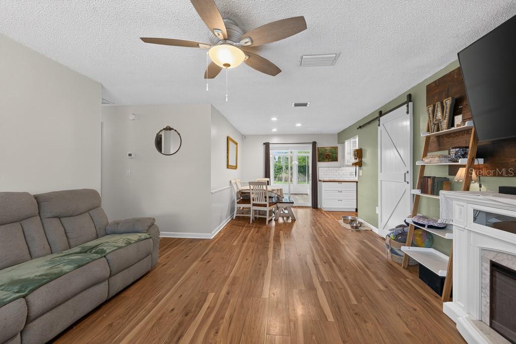 A living room with wood flooring, a ceiling fan, a barn door, and a dining area — 6070 73RD STREET N, ST PETERSBURG, FL