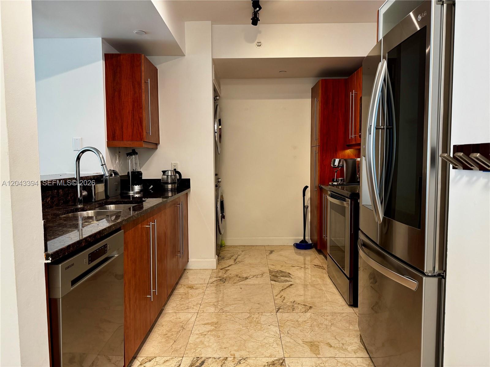 A galley kitchen features wood cabinets, dark granite countertops, stainless steel appliances, and tile flooring — 7350 SW 89th St # 1809S, Miami FL 33156, MIAMI, FL