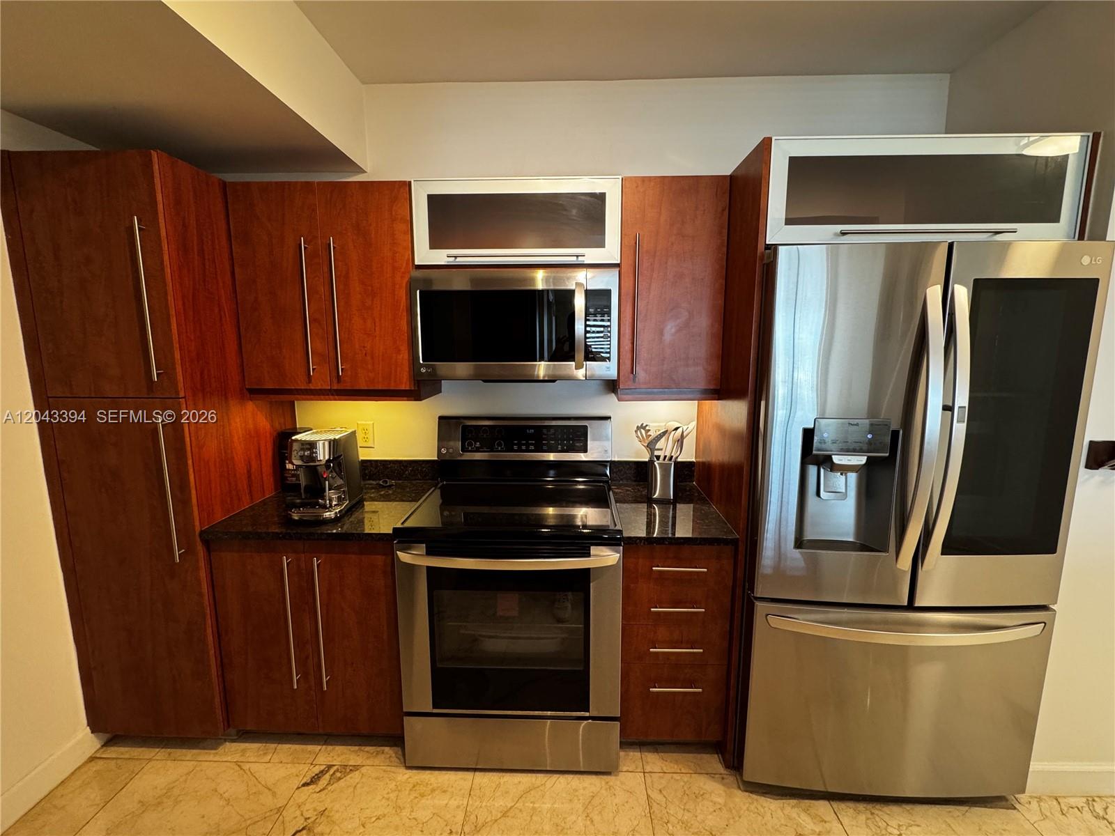 A kitchen features dark wood cabinets, stainless steel appliances, and a granite countertop — 7350 SW 89th St # 1809S, Miami FL 33156, MIAMI, FL