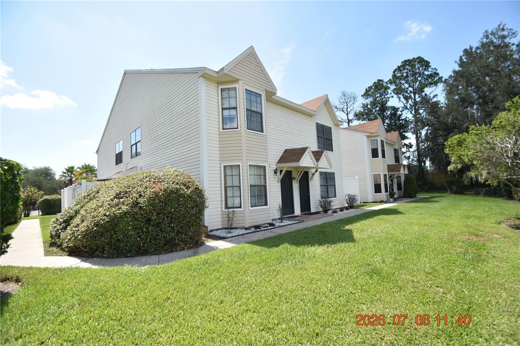 A two-story townhouse with light-colored siding and a grassy lawn in front — 2302 MAKI ROAD UNIT 2, PLANT CITY, FL