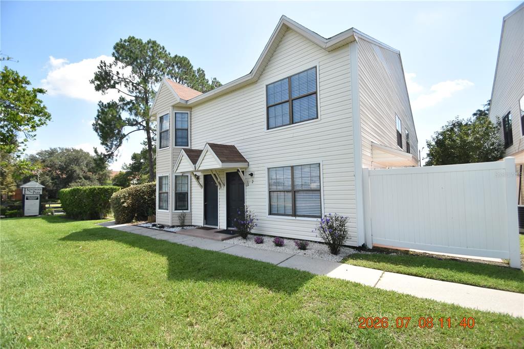 A two-story, light-colored vinyl-sided duplex with two front entrances and a white privacy fence — 2302 MAKI ROAD UNIT 2, PLANT CITY, FL