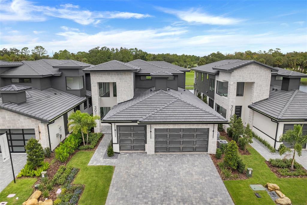 An aerial view shows the exterior of two modern townhomes with gray tile roofs — 3015 KENSINGTON AVENUE, DAVENPORT, FL