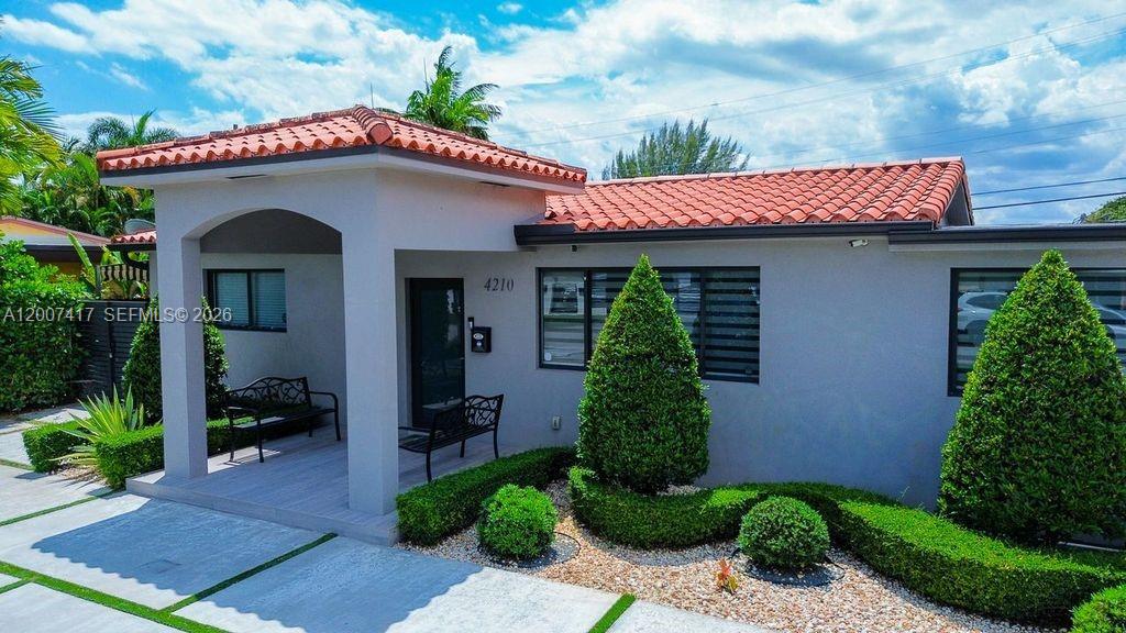 A single-story house with a terracotta tile roof, a covered porch, and manicured landscaping — 4210 W 6th Ave, Hialeah FL 33012, HIALEAH, FL