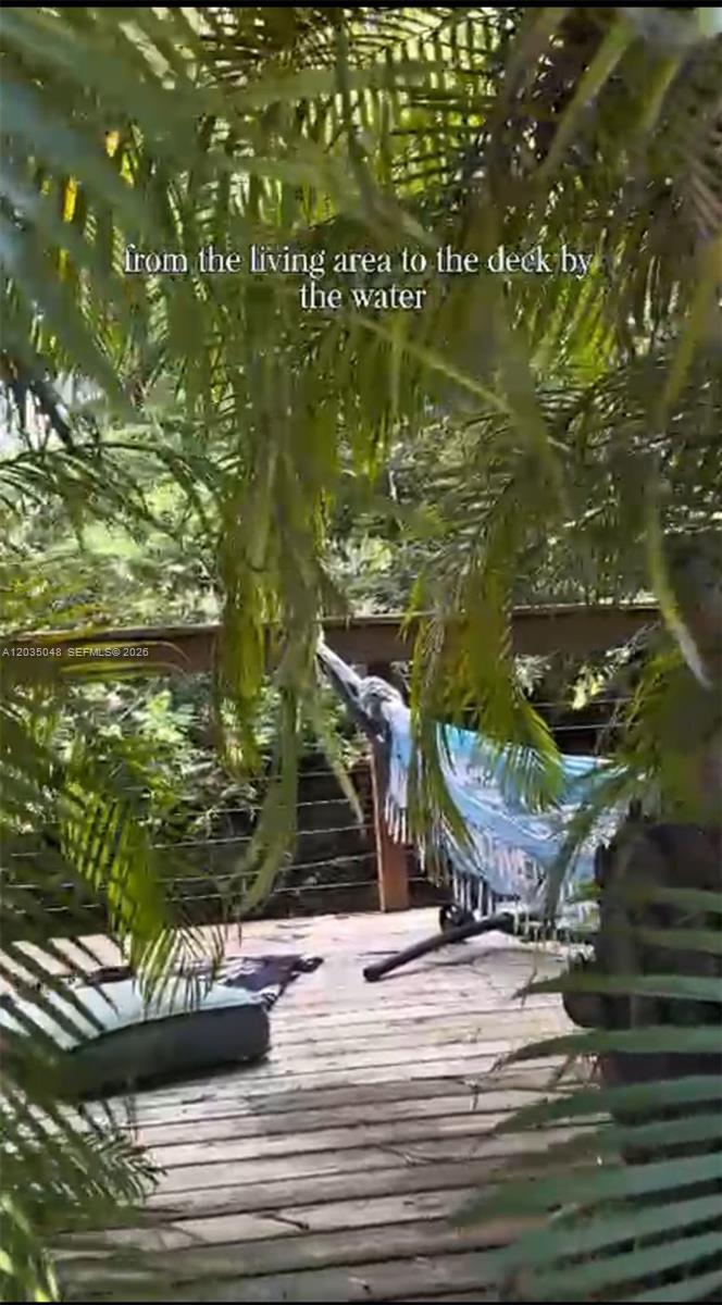 A wooden deck features a hammock and lush greenery overlooking a body of water — 6560 SW 189th Way, Southwest Ranches FL 33332, SOUTHWEST RANCHES, FL