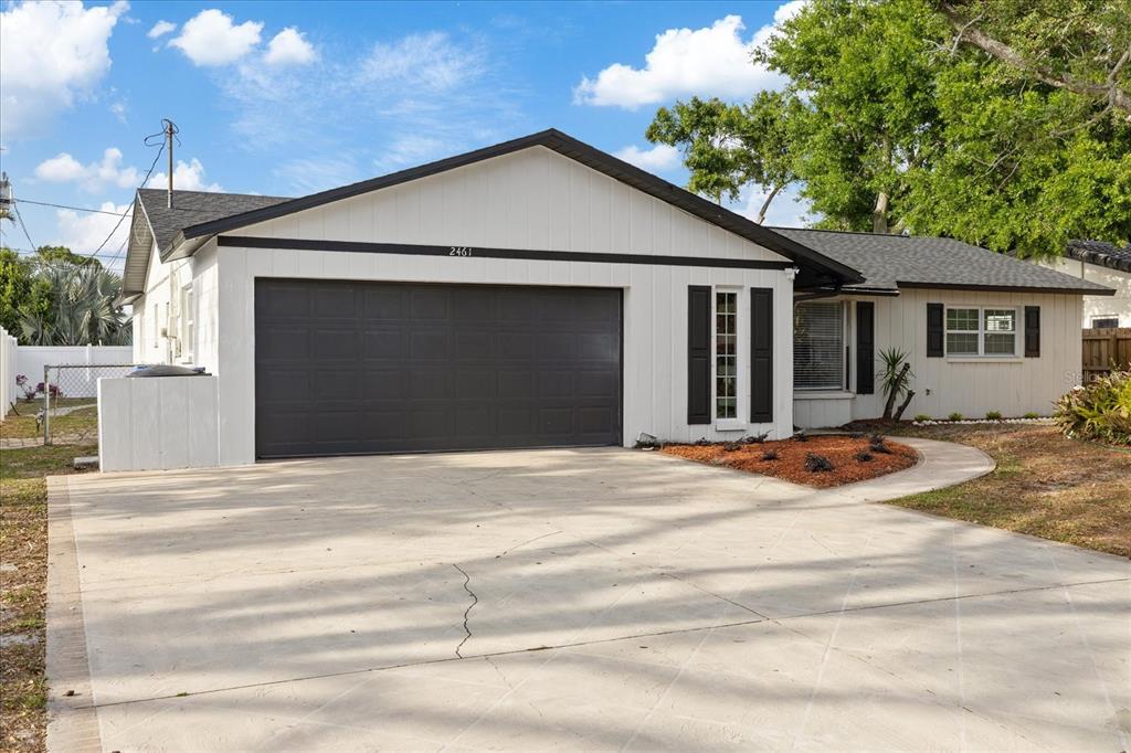 A single-story house with a white exterior, dark trim, and a two-car garage — 2461 69TH AVENUE S, ST PETERSBURG, FL