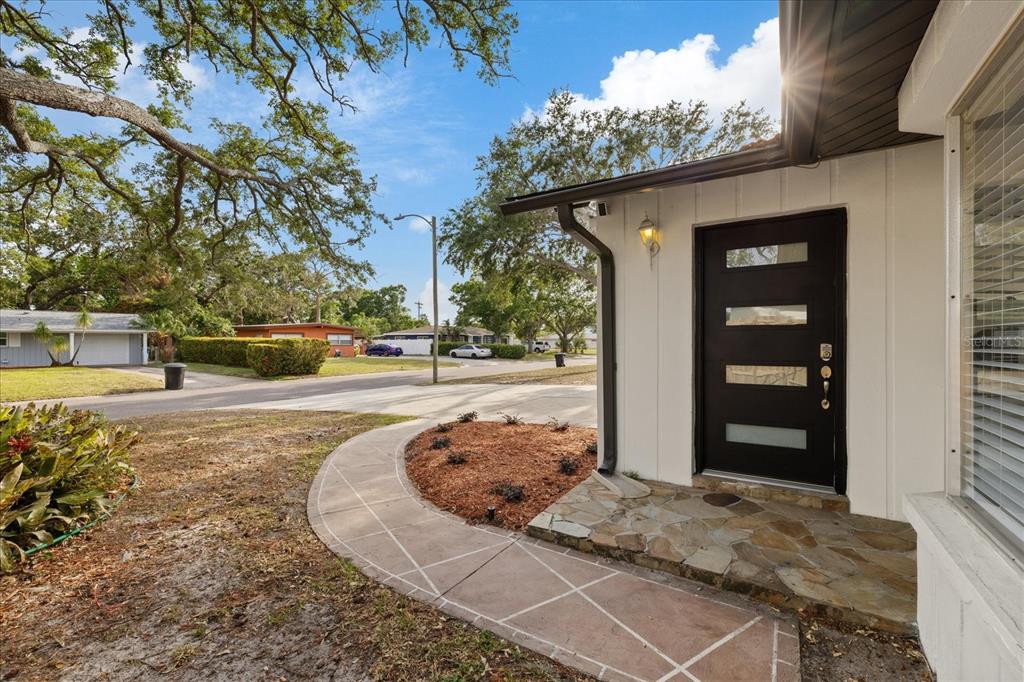 A curved walkway leads to the front entrance of a house with a black door — 2461 69TH AVENUE S, ST PETERSBURG, FL