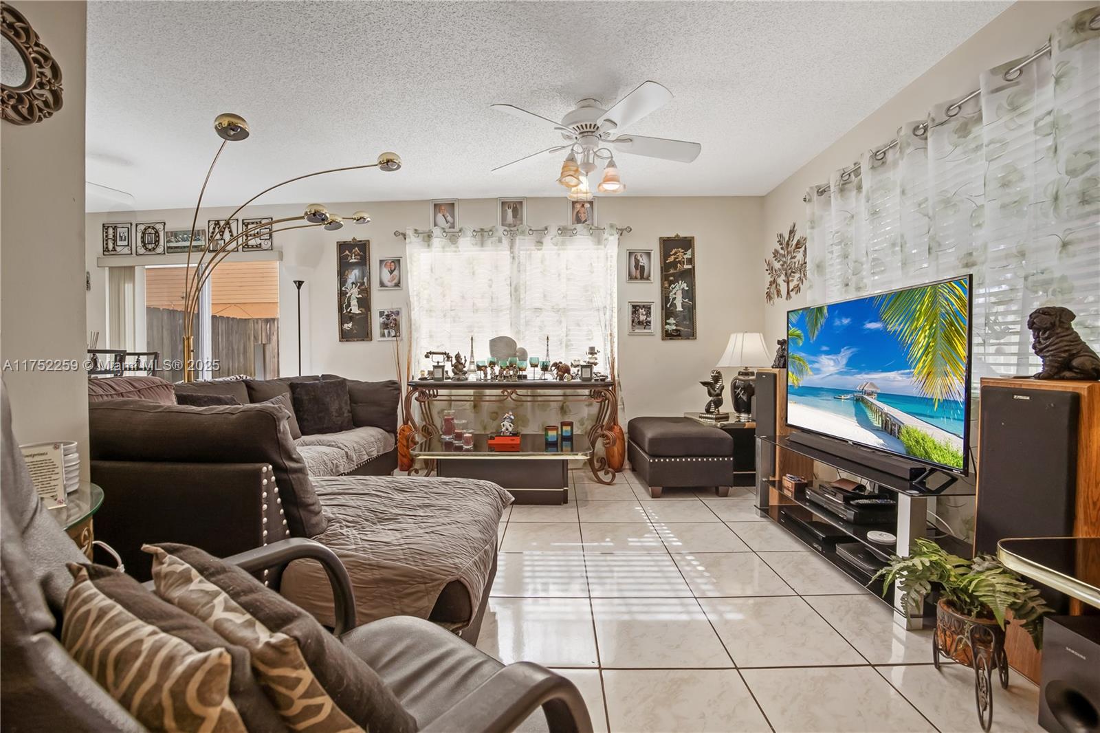A living room features tile flooring, a ceiling fan, a sectional sofa, and a television — 265 NE 12th Ave # 265, Homestead FL 33030, HOMESTEAD, FL