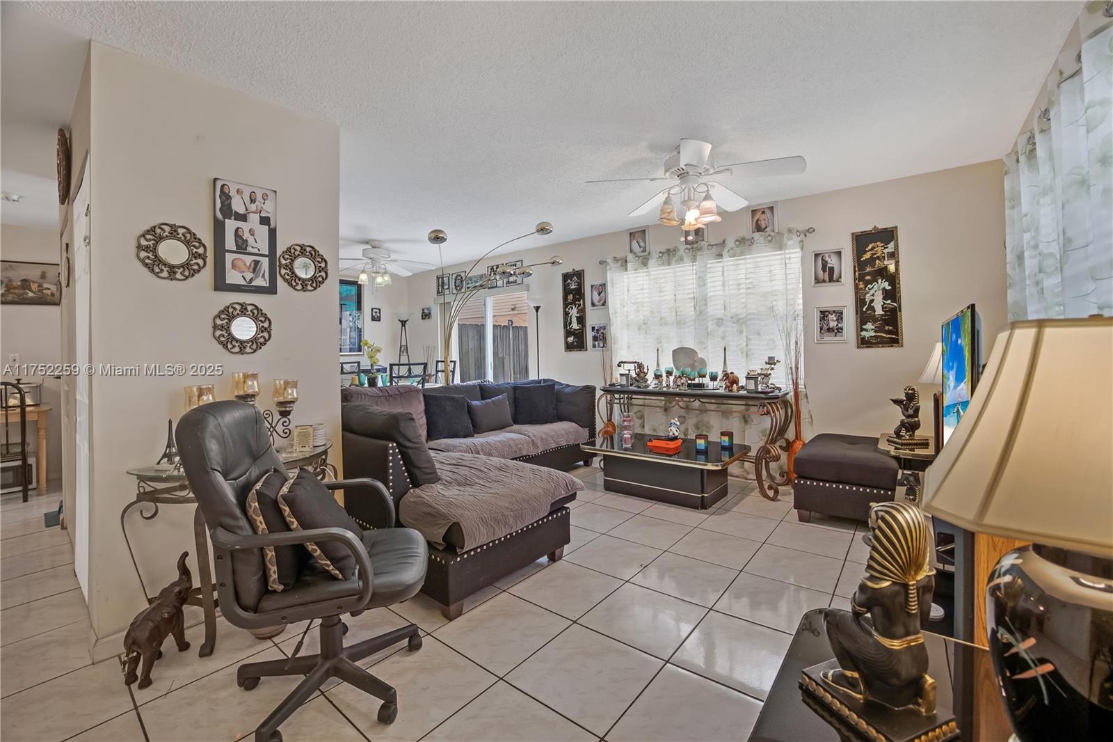 A living room features tile flooring, a dark sectional sofa, and a ceiling fan — 265 NE 12th Ave # 265, Homestead FL 33030, HOMESTEAD, FL