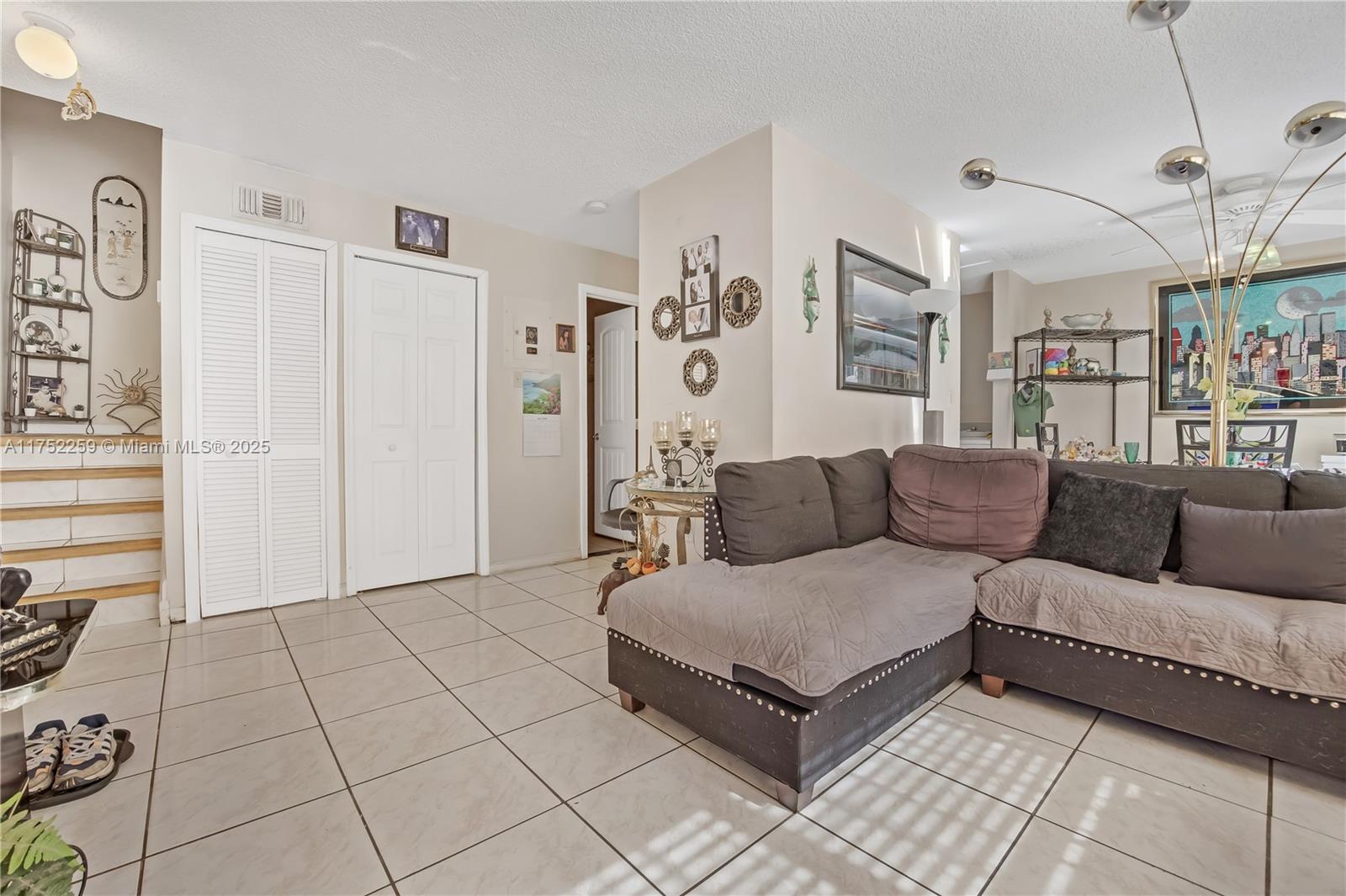 A living room features a large sectional sofa, tiled floors, and a multi-arm floor lamp — 265 NE 12th Ave # 265, Homestead FL 33030, HOMESTEAD, FL