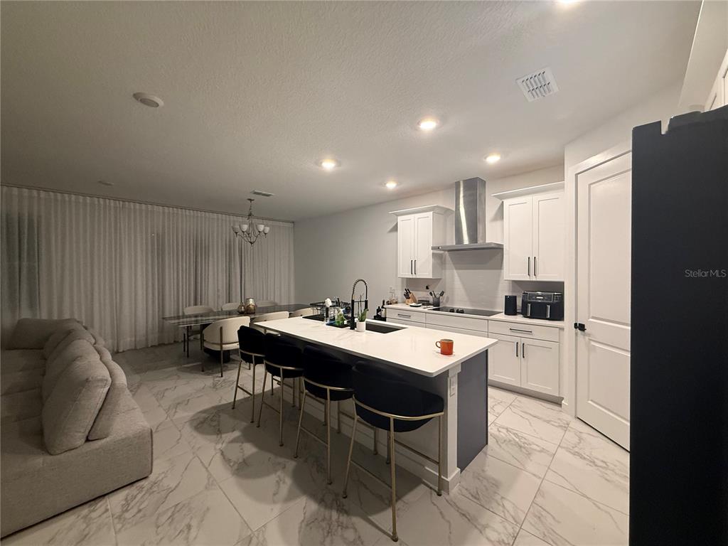 An open-concept kitchen features a central island, white cabinetry, and marble-patterned tile flooring — 2252 GOLD SUMMIT STREET, MINNEOLA, FL