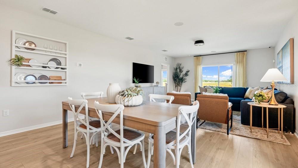 An open-concept dining and living area features light wood flooring, white chairs, and neutral walls — 136 BRINSMEAD ROAD, HAINES CITY, FL