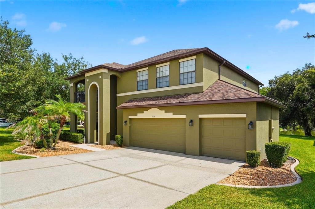 A two-story house with an olive green exterior, a three-car garage, and a covered entryway — 268 OAK LANDING LANE, MULBERRY, FL