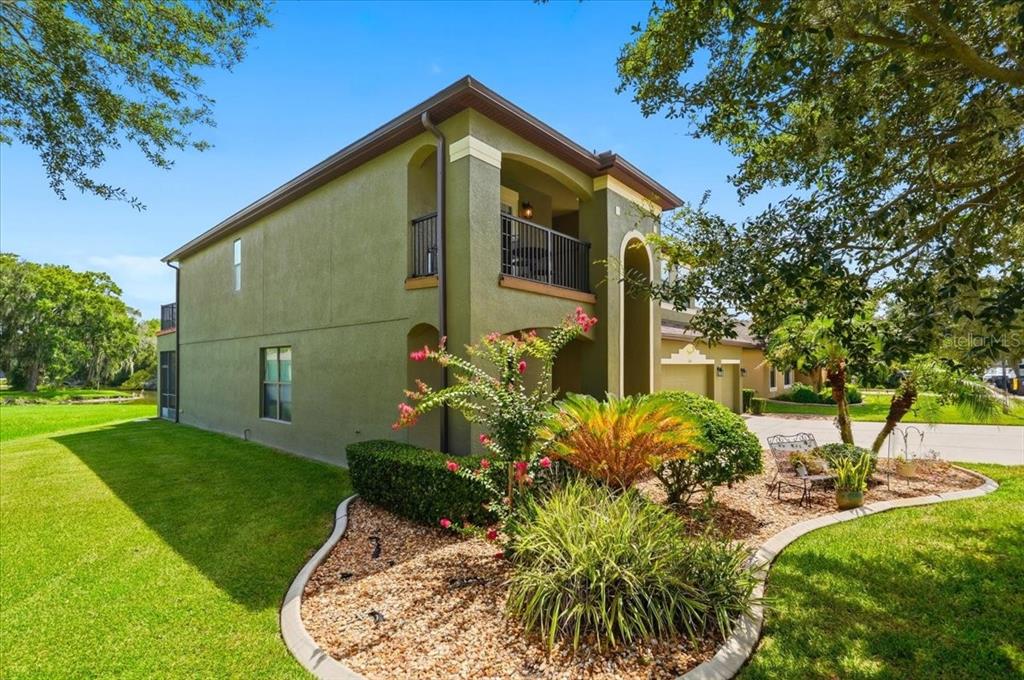 A two-story green stucco house with a balcony and a landscaped front garden — 268 OAK LANDING LANE, MULBERRY, FL