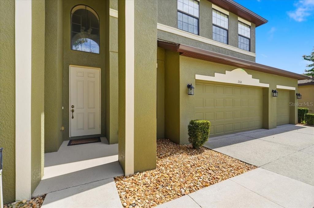 A two-story house exterior features olive green stucco, a white front door, and a garage — 268 OAK LANDING LANE, MULBERRY, FL