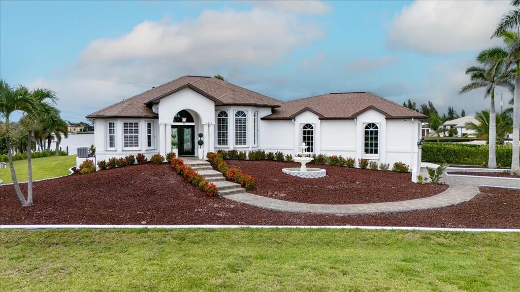A white single-story house with a brown roof, a stone walkway, and a front fountain — 4213 NW 28TH STREET, CAPE CORAL, FL